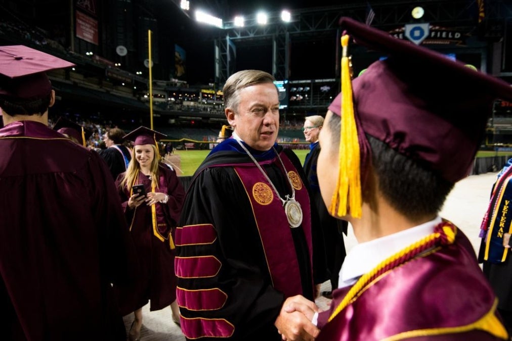 ASU President Michael Crow shakes hands with an ASU graduate at University Commencement