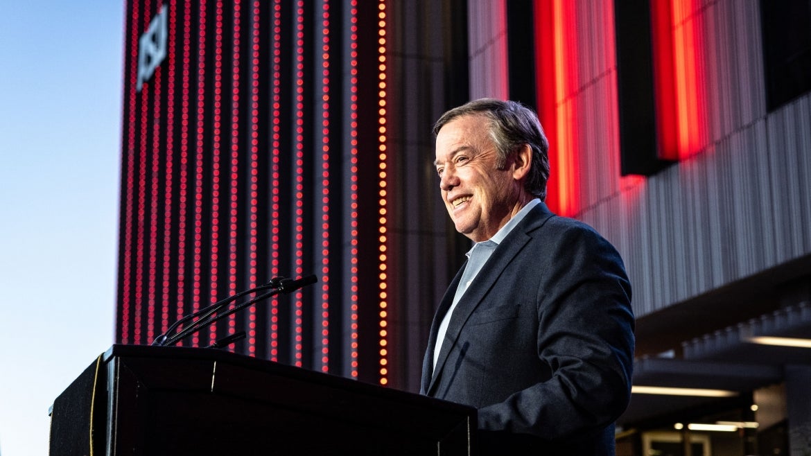 President Crow smiling while standing at a podium