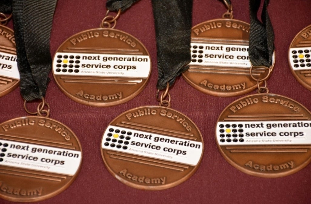 A table full of ASU Next Generation Service Corps medals with black ribbons. 