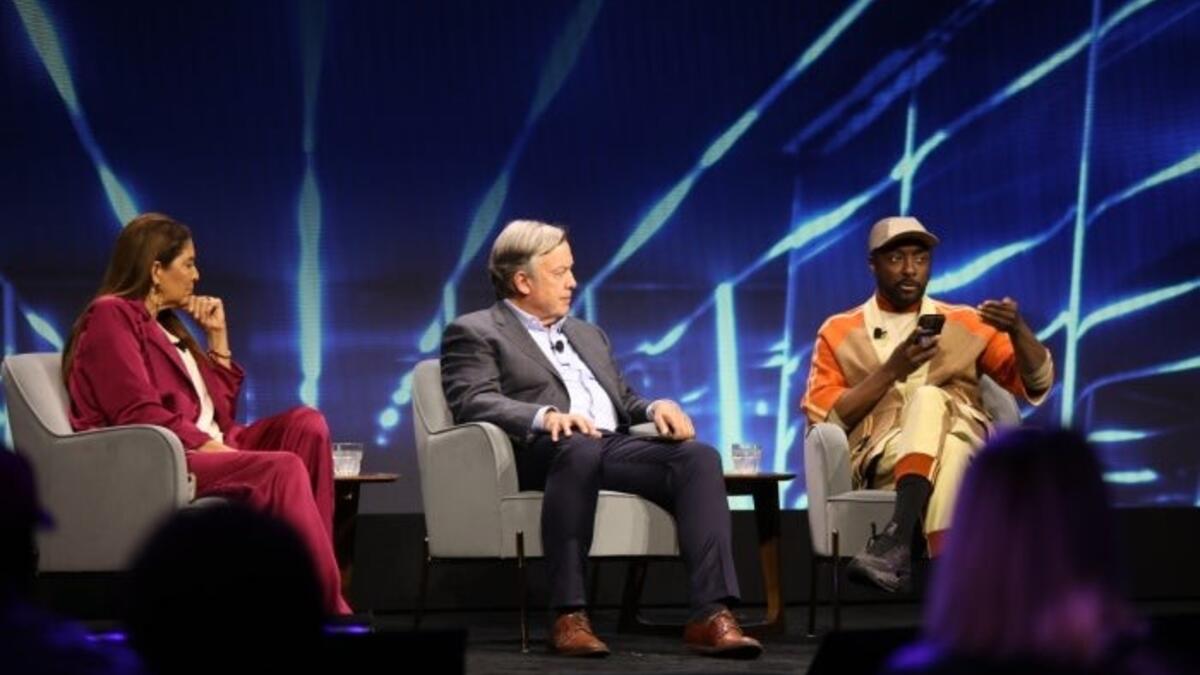 Three media and technology leaders sit on-stage in conversation about the future of AI and education. 