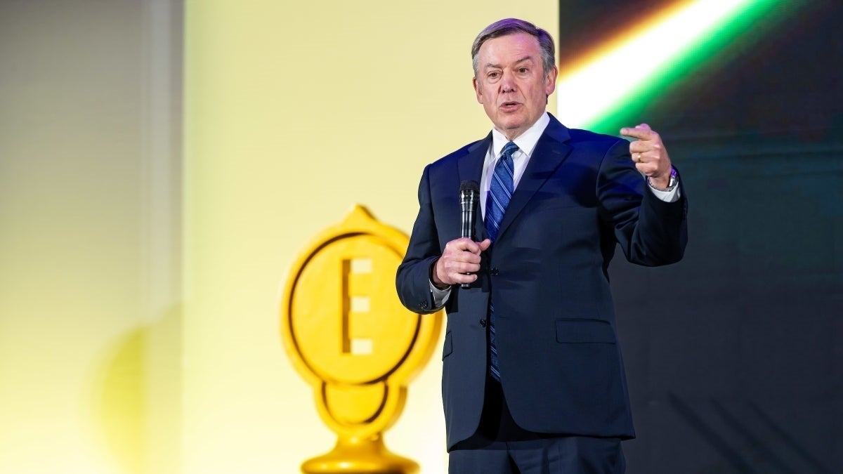 A person in a blue suit and tie speaks into a microphone while accepting the 2025 Edison Achievement Award. 