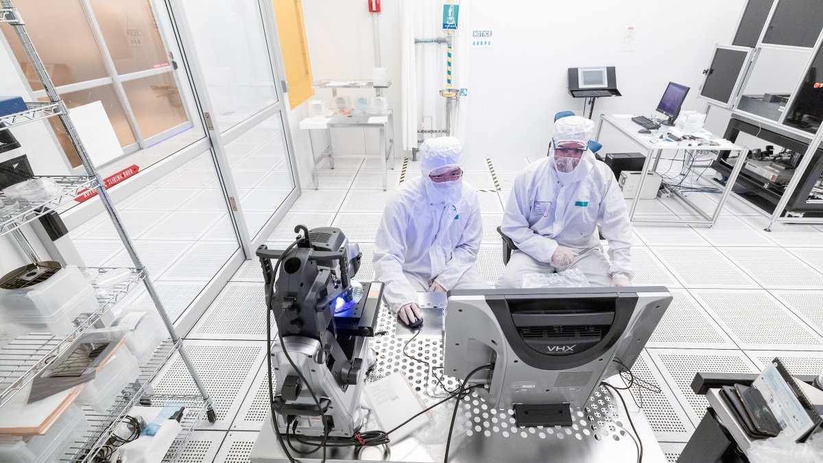 Two researchers in "bunny" suits work in a clean room