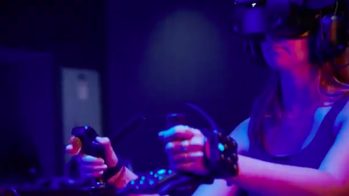 A student uses a VR headset uses electronic joysticks to participate in a biology lab course. 